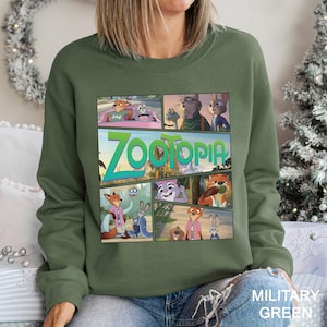 May include: Military green sweatshirt featuring a comic strip design with characters and the title "Zootopia". The design includes various scenes from the animated movie. The sweatshirt is made of a soft material.
