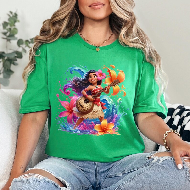May include: A green t-shirt featuring a vibrant illustration of a cartoon character playing a ukulele. The character is adorned with flowers and surrounded by colorful water and floral elements. The shirt is a solid green color.