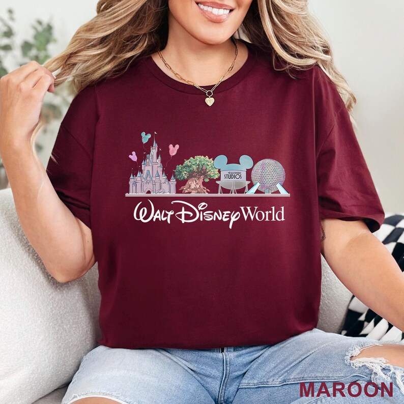 May include: Maroon t-shirt featuring a Walt Disney World design. The graphic includes a castle, tree, Mickey Mouse ears, and a sphere. The text "Walt Disney World" is written in a cursive font. The word "MAROON" is written in a block font.