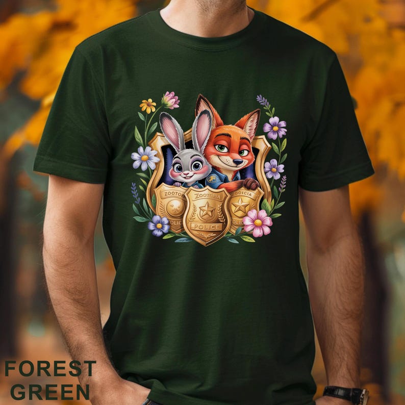 Puede incluir: Camiseta verde bosque con un gr&aacute;fico colorido de Judy Hopps y Nick Wilde de Zootr&oacute;polis, enmarcado por flores y escudos de polic&iacute;a. El texto "Zootopia Police" es visible en los escudos. La camiseta es de material suave.