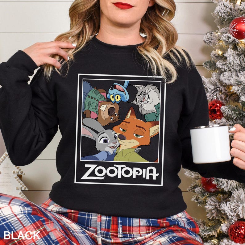 Peut inclure: Sweat-shirt noir avec un imprim&eacute; Zootopia. L'imprim&eacute; comprend Judy Hopps, Nick Wilde et d'autres personnages du film d'animation. Le mot "Zootopia" est imprim&eacute; en blanc. Le sweat-shirt est port&eacute; par une personne.