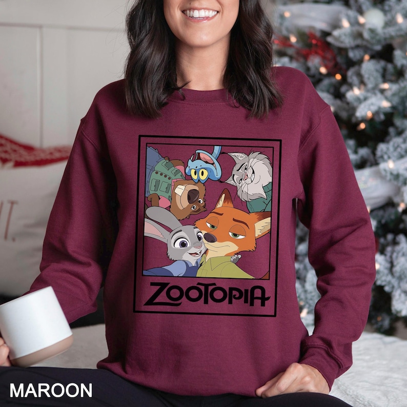 Peut inclure: Sweat-shirt bordeaux avec un motif Zootopia. Le motif comprend des personnages du film d'animation, avec le mot "ZOOTOPIA" dans un cadre noir. Le sweat-shirt est de couleur bordeaux unie.