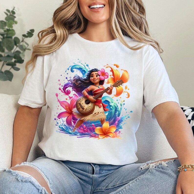 May include: White t-shirt featuring a vibrant illustration of a cartoon character playing a ukulele. The design includes colorful flowers and water splashes, creating a tropical theme. The character is wearing a flower in their hair and a traditional outfit.
