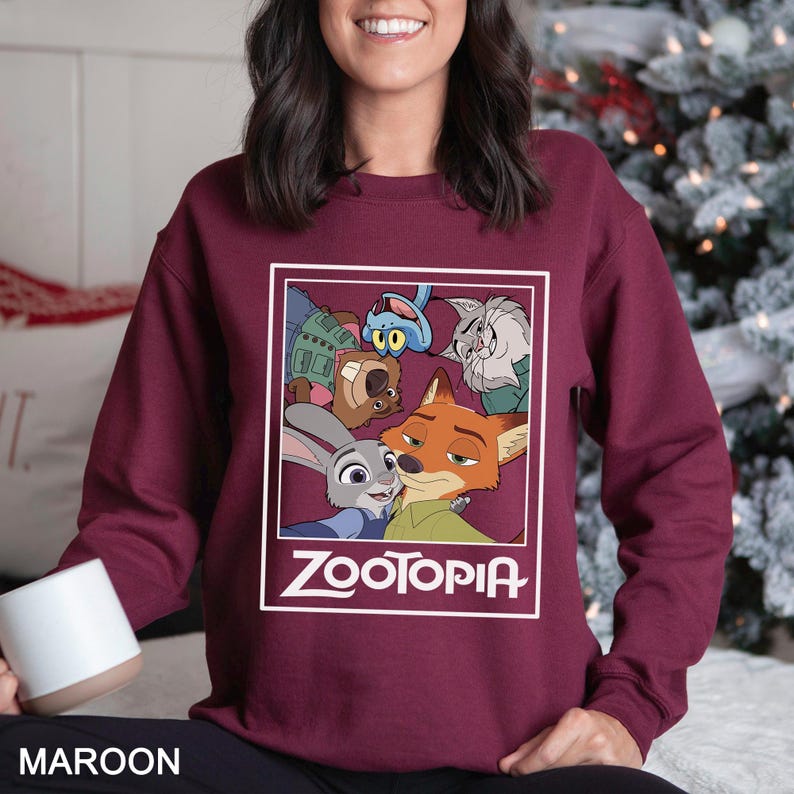Peut inclure: Sweat-shirt bordeaux avec un motif encadr&eacute; des personnages du film d'animation "Zootopia". Le motif comprend Judy Hopps, Nick Wilde et d'autres personnages. Le mot "Zootopia" est imprim&eacute; en blanc en dessous.
