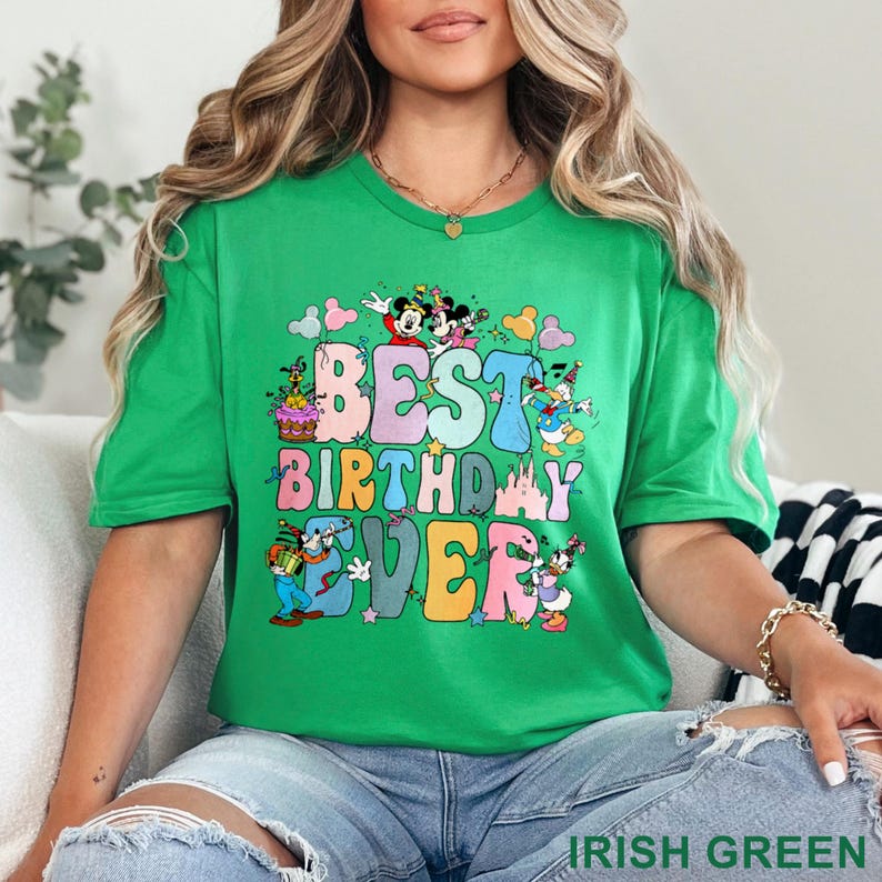 May include: A green t-shirt with the text "BEST BIRTHDAY EVER" in colorful bubble letters. The design includes cartoon characters like Mickey and Minnie Mouse, Donald Duck, and Daisy Duck. The shirt is a vibrant shade of green.
