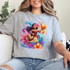 May include: A heather gray t-shirt featuring a vibrant illustration of a cartoon character playing a ukulele. The design includes colorful flowers, water splashes, and a tropical theme. The character is wearing a flower in their hair and a red and white outfit.