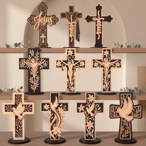 May include: A collection of ten standing wooden crosses featuring intricate laser-cut designs. The crosses display various motifs including the word Jesus, floral patterns, doves, and depictions of the crucifixion in black and light wood tones.
