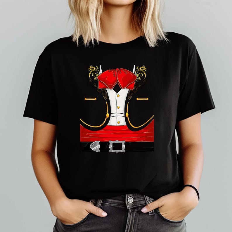 May include: Black t-shirt featuring a graphic of a mariachi outfit. The design includes a red bow tie, a white shirt, a black jacket with gold trim, and a red belt with a silver buckle. The graphic is centered on the shirt.