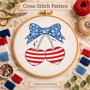 Pode incluir: Um padrão de ponto cruz com um laço com um padrão de estrelas azuis e duas cerejas com listras vermelhas e brancas. O desenho está num bastidor de bordado de madeira. O texto "Cross Stitch Pattern" e "(Digital Download)" são visíveis.