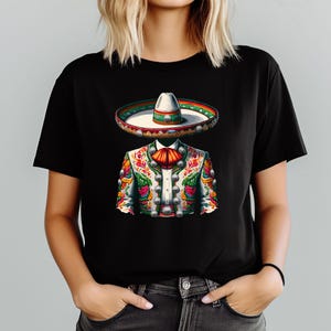 May include: Black t-shirt featuring a colorful illustration of a traditional Mexican mariachi outfit. The design includes a sombrero, a decorated jacket with silver buttons, and a red bow tie. The artwork is vibrant and detailed.