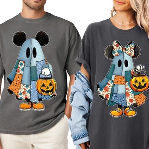 Pode incluir: Duas camisetas cinzentas com um personagem de fantasma de desenho animado com orelhas do Mickey Mouse, roupas de patchwork e uma lanterna de abóbora. O fantasma está segurando um balde de abóbora. O design inclui padrões laranja, azul e floral, perfeito para o Halloween.