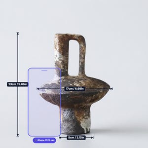 May include: A ceramic vase with a textured, mottled brown and black finish, featuring a central handle and a wide, rounded midsection. The vase measures 9.06 inches in height, 6.69 inches in width, and has a base diameter of 3.15 inches.