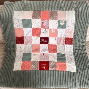 Peut inclure: Une courtepointe patchwork verte et rose avec un nom personnalisé "Rose" brodé au centre. La courtepointe est faite de différents tissus avec des motifs floraux et animaliers.