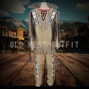 Puede incluir: Un atuendo nativo americano de color beige, que incluye una camisa y pantalones, exhibido en un maniquí. La camisa presenta flecos, abalorios y un diseño geométrico. Los pantalones también tienen abalorios. El texto "OLD WEST OUTFIT" es visible.