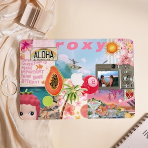 Può includere: Un tappetino per mouse rettangolare con marchio Roxy con un collage di immagini tropicali. Presenta una targa di immatricolazione delle Hawaii, una papaya, una fotocamera digitale e la parola "ALOHA". Il design è vibrante, con rosa, arancione e blu.