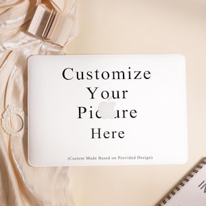 May include: A white laptop with the text "Customize Your Picture Here" in black. The laptop is on a cream-colored surface with a small book and decorative elements.