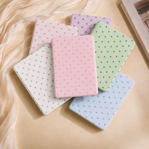 May include: A collection of five rectangular notebooks with rounded corners, each featuring a pastel-colored cover with a repeating polka dot pattern in shades of pink, light blue, lavender, and light green, arranged in a layered stack.