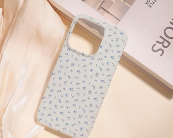 May include: A light-colored phone case with a delicate floral pattern of small blue flowers. The case has a smooth finish and a cutout for the camera and buttons. The case is designed to protect the phone from scratches and damage.