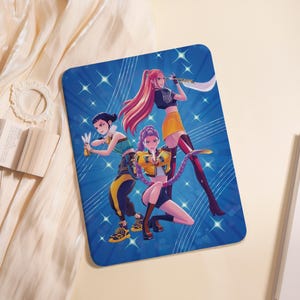 May include: A blue rectangular blanket featuring a vibrant illustration of three anime-style characters. The characters are depicted in dynamic poses, wielding weapons against a backdrop of radiating blue lines and star-shaped accents. The characters wear stylish outfits in yellow, black, and green.