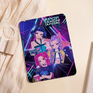 May include: A rectangular K-Pop Demon Hunters design featuring three anime-style female characters with vibrant hair colors. The design includes a star and neon lines against a dark background. Each character holds a cup.