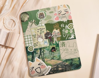 Könnte beinhalten: Eine rechteckige Tablethülle mit einer Collage aus grün getönten Illustrationen, darunter Totoro-Figuren, Waldszenen und gezeichnete Katzen. Das Design enthält verschiedene Aufkleber, japanischen Text und grafische Muster auf einem Waldhintergrund.