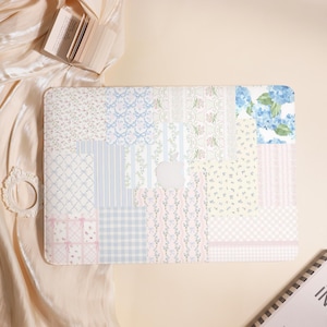 May include: A laptop case with a patchwork design featuring floral, gingham, and striped patterns in pastel colors. The case has a cutout for the Apple logo and a soft, feminine aesthetic.