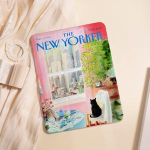 Puede incluir: Una bandeja decorativa rectangular con una colorida ilustración de una portada de la revista New Yorker. La portada representa una habitación con vista a la ciudad, un gato negro y una mesa puesta para el té. El texto "THE NEW YORKER" se muestra de forma destacada.