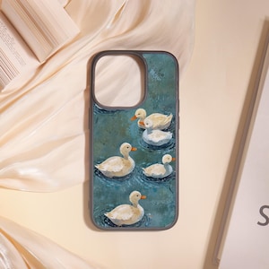 May include: A phone case with a painting of six white ducks on a teal pond. The ducks have orange beaks and are set against a textured background. The case has a grey border and is displayed on a cream surface. The case is for a mobile phone.
