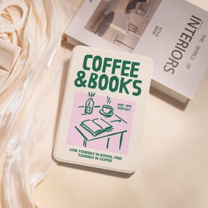 Peut inclure: Un carnet crème avec les mots "COFFEE & BOOKS" en vert. Le carnet comporte un rectangle rose avec une illustration de tasse à café, de livre ouvert et de vase. Le texte "LOSE YOURSELF IN BOOKS, FIND YOURSELF IN COFFEE" est en bas.
