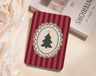 May include: A rectangular Christmas-themed decorative item with a red and white striped background. The center features an oval design with a green Christmas tree and a yellow star on top, framed by a white scalloped border. The item is placed on a cream-colored surface.