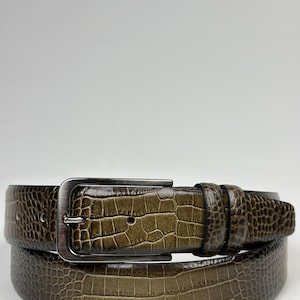 Peut inclure: Une ceinture marron avec un motif textur&eacute; en forme de crocodile. La ceinture a une boucle rectangulaire de couleur argent&eacute;e. La ceinture en cuir est de couleur marron moyen et est con&ccedil;ue pour un usage quotidien.