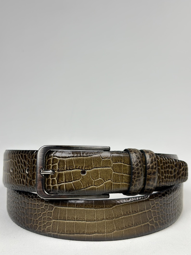 Peut inclure: Une ceinture marron avec un motif textur&eacute; en forme de crocodile. La ceinture a une boucle rectangulaire de couleur argent&eacute;e. La ceinture en cuir est de couleur marron moyen et est con&ccedil;ue pour un usage quotidien.