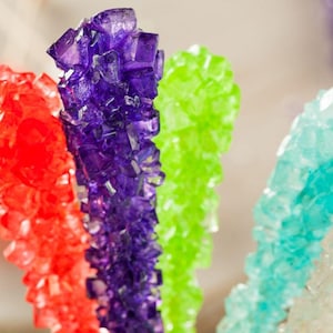 Può includere: Cinque bastoncini di zucchero filato colorati, rosso, viola, verde, blu e bianco. Il dolce è fatto di cristalli di zucchero.
