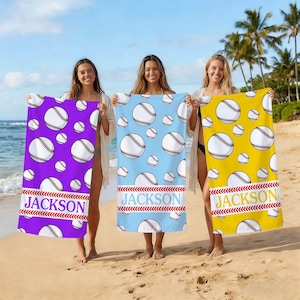 May include: Three beach towels with baseball designs. One is purple, one is light blue, and one is yellow. Each towel has a repeating pattern of baseballs and the name "JACKSON" in a red and white design.