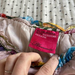 Puede incluir: Top de seda rosa con estampado floral y una etiqueta rosa que dice "We are in love with Salvatore Piccione Blumarine".