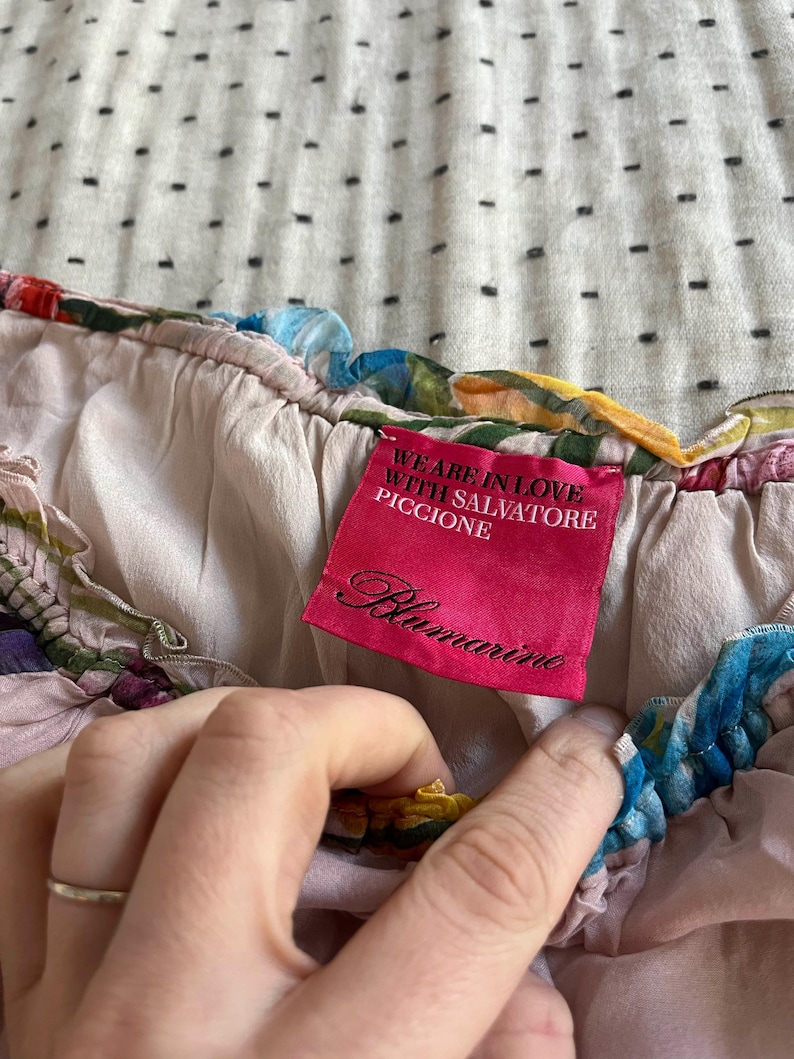Puede incluir: Top de seda rosa con estampado floral y una etiqueta rosa que dice "We are in love with Salvatore Piccione Blumarine".