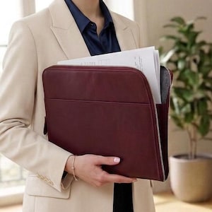 May include: A dark burgundy document portfolio case with a smooth finish and a side zipper closure. The rectangular case features a front pocket and is shown holding white papers, providing a structured and professional storage solution for documents.