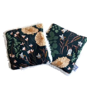 May include: Two green fabric hand warmers with a floral print. The warmers have a white sherpa lining and are perfect for keeping your hands warm in the winter.