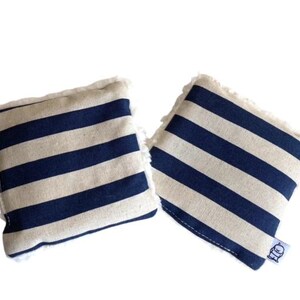 May include: Two blue and white striped fabric squares with frayed edges. The squares are made of a soft, natural fabric and have a subtle texture. The fabric squares are perfect for adding a touch of nautical style to any room.