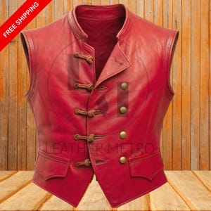 Pode incluir: Um colete de couro vermelho com gola mandarim e fechos de altern&acirc;ncia decorativos. O colete apresenta dois bolsos frontais e bot&otilde;es de cor lat&atilde;o. O texto "LEATHER METRO" &eacute; vis&iacute;vel.