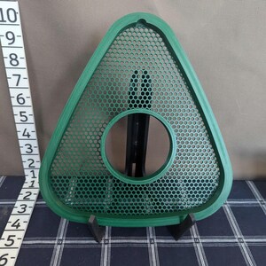 May include: A green, triangular object with a perforated surface and a circular opening. The object is approximately 9 inches tall and is supported by a black stand. The design features a honeycomb pattern.