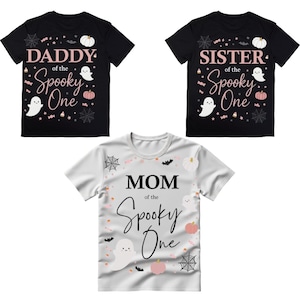 May include: Three Halloween-themed t-shirts. Two black shirts read "DADDY of the Spooky One" and "SISTER of the Spooky One". The third shirt is white and reads "MOM of the Spooky One". Each shirt features a ghost, pumpkin, and spiderweb design.