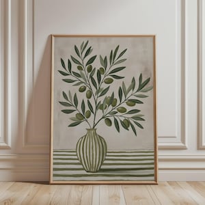 Könnte beinhalten: Ein gerahmter Kunstdruck mit einem vertikalen Gemälde eines Olivenzweigs mit grünen Blättern und Oliven in einer gestreiften Vase. Die Vase steht auf einer Fläche mit horizontalen grünen und weißen Streifen vor einem neutralen, beigen Hintergrund.