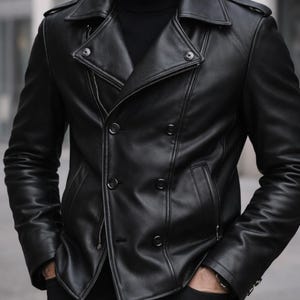 Peut inclure: Veste en cuir noire à double boutonnage. La veste présente un col cranté, une fermeture éclair et des boutons. Elle possède deux poches avant et une coupe ajustée.