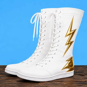 Puede incluir: Un par de botas blancas de media caña con cordones frontales blancos y una aplicación de rayo en color dorado metálico en el lado exterior. Las botas cuentan con una suela plana blanca y un acabado liso, llegando hasta la mitad de la pantorrilla.