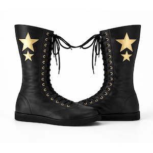 May include: A pair of black, lace-up boots with gold star accents. The boots have a flat sole and a tall shaft, with eyelets for the laces. Gold stars are on the side of each boot.