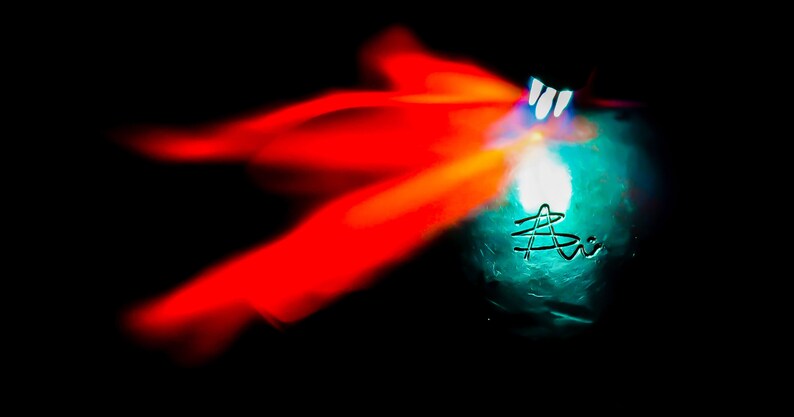 May include: A blue glass orb with a white light shining through it. The orb is surrounded by a red and orange blur.