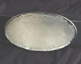May include: A silver oval-shaped belt buckle with a textured surface.
