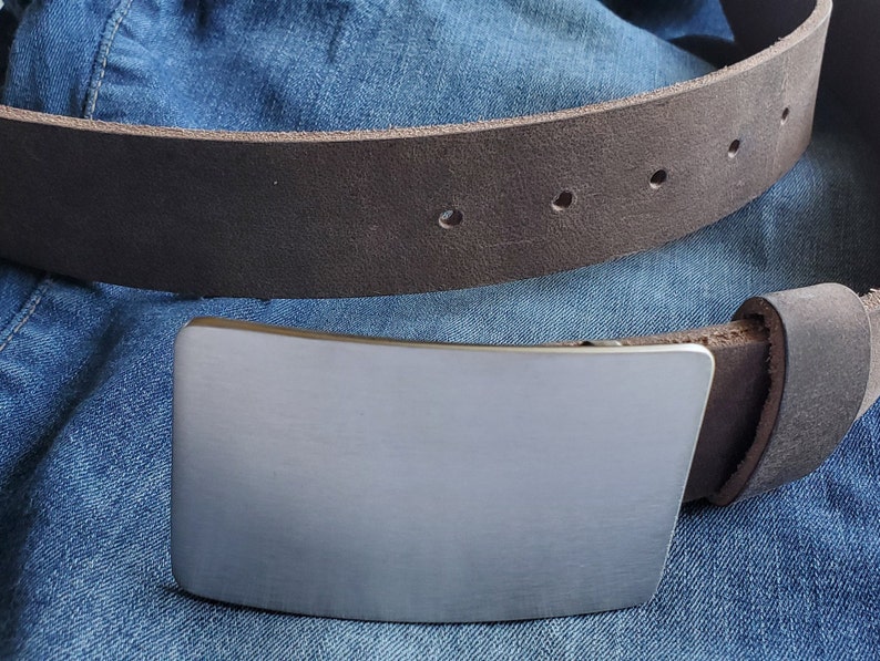 May include: A brown leather belt with a silver buckle. The buckle is rectangular and has a smooth, brushed finish.