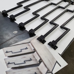 May include: Six black metal drawer pulls with a zig-zag design. The pulls are shown on a white surface with a drawing of a three-drawer dresser with the pulls installed.